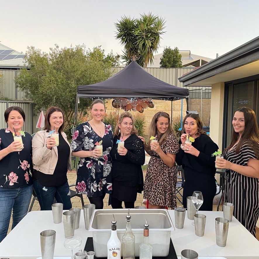 A group cheering at a backyard party in Perth with a marquee behind them
