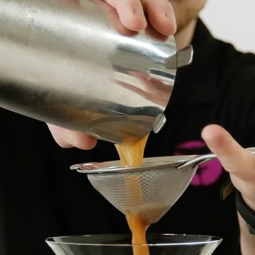 An espresso martini being strained into a glass